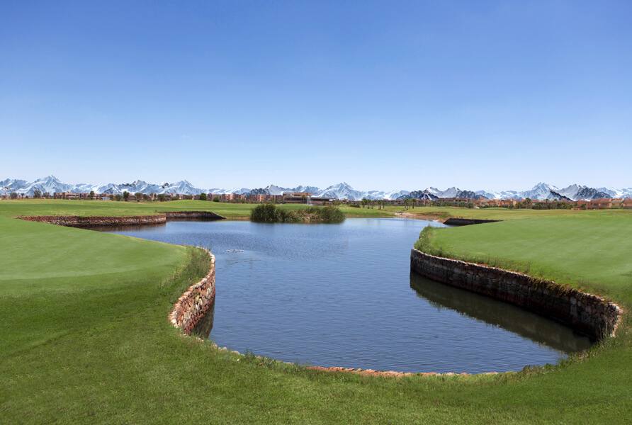 The Montgomerie Marrakech : obstacle d'eau entre deux greens, Atlas enneigé